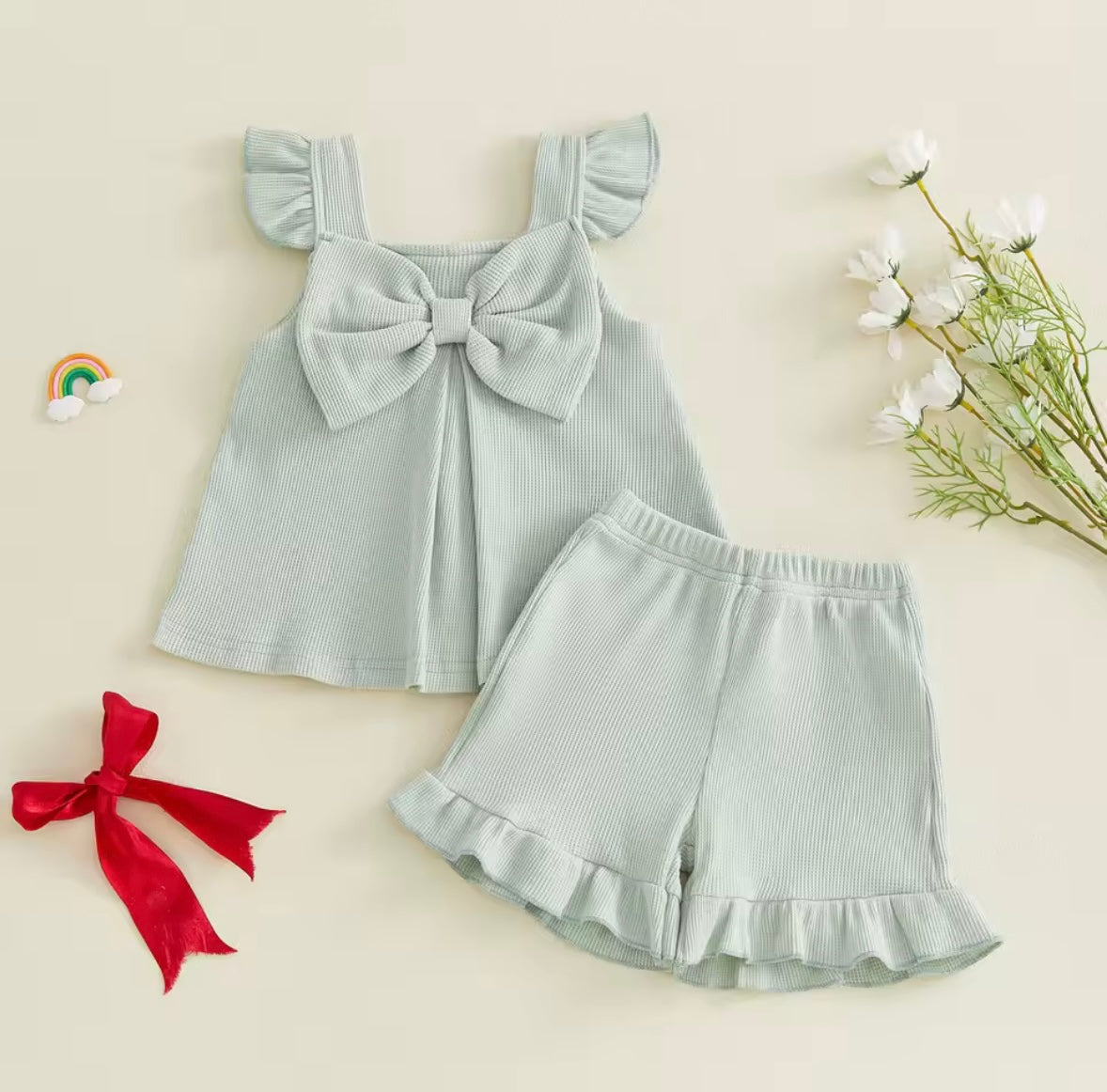 Light blue children's outfit with a bow on a beige background