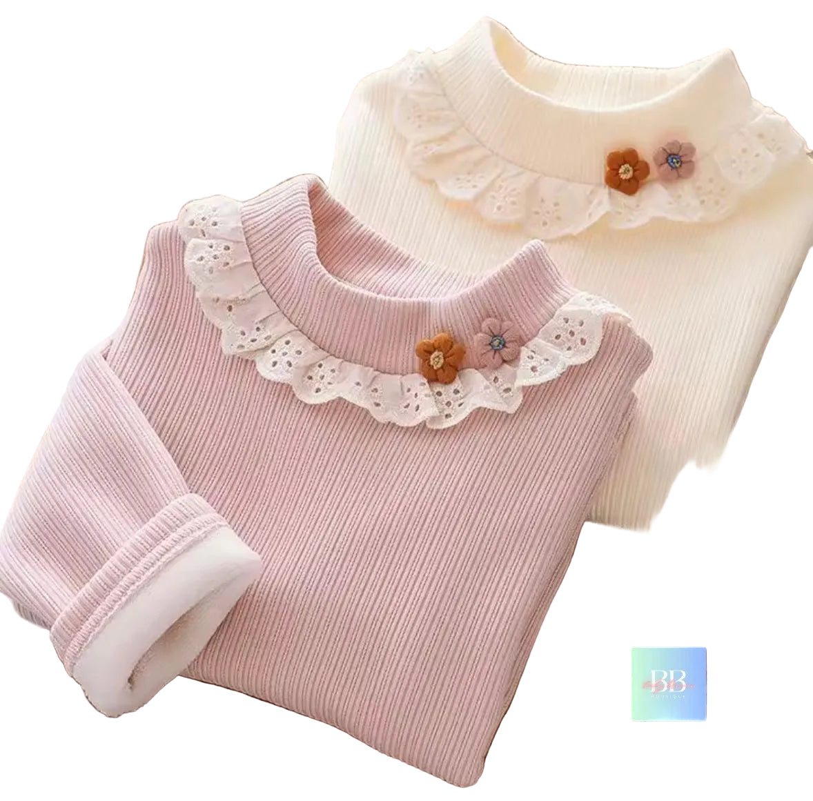 Two ribbed knit shirts with lace collars and floral details on a wooden surface.