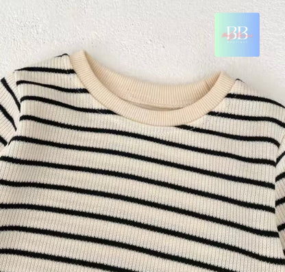 Close-up of a black and white striped sweater with a brand logo in the corner.