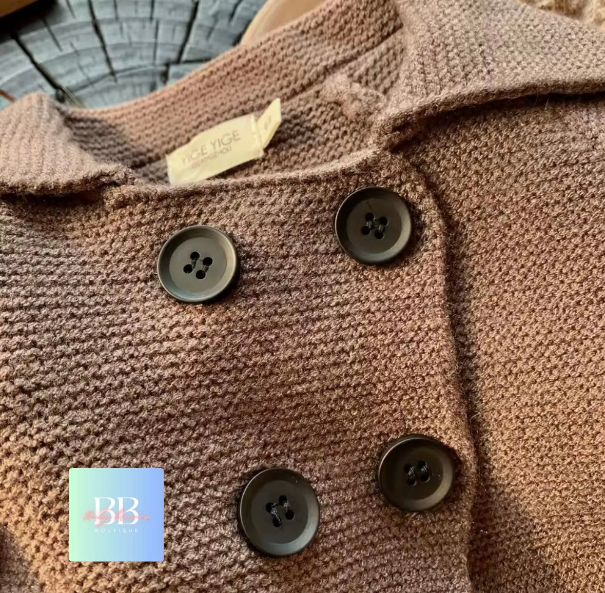 Close-up of a brown textured garment with buttons and a visible brand tag.