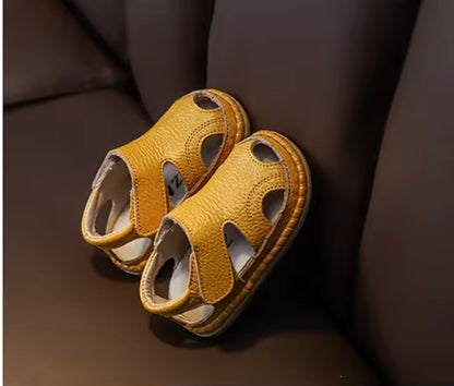 Pair of yellow sandals on a dark brown surface