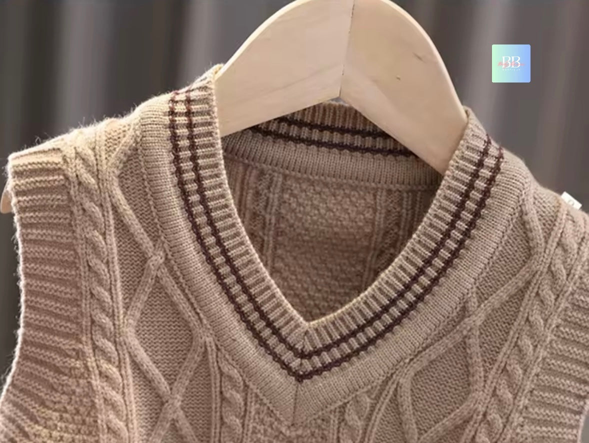 Beige cable knit sweater on a hanger against a dark background