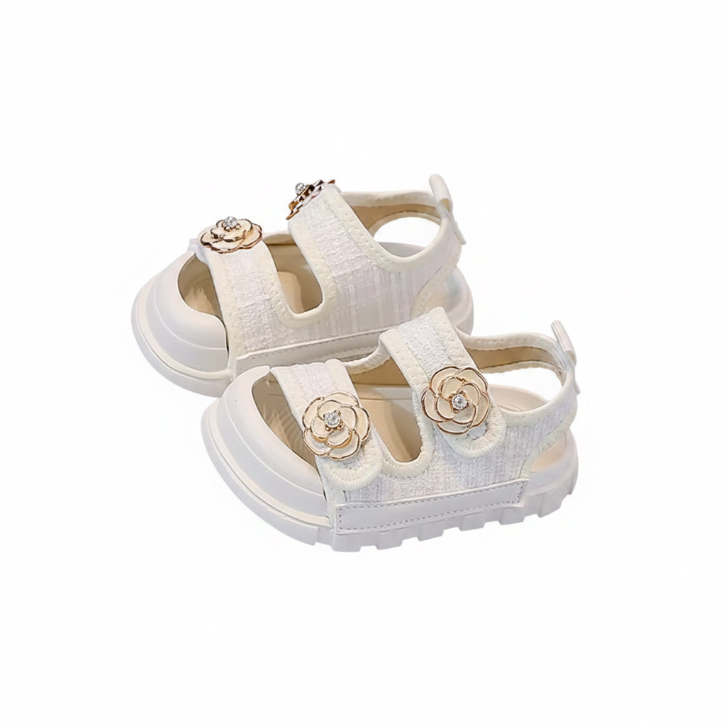 White children's sandals with floral decorations on a book