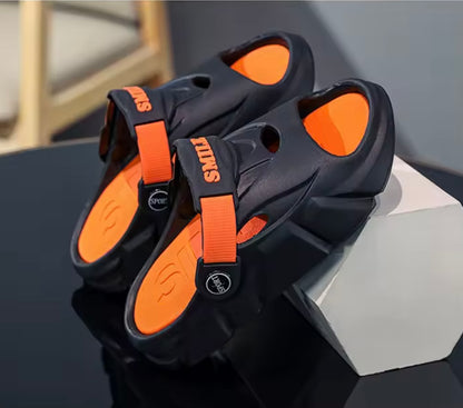 Black and orange sandals on a dark surface with a light gray background