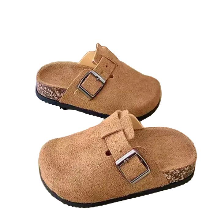 Pair of brown suede clogs with buckles on a light surface.