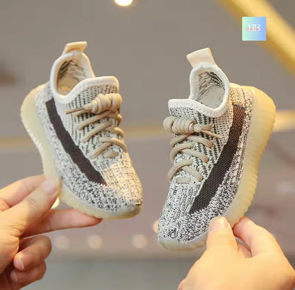 Pair of baby shoes held by two hands against a neutral background