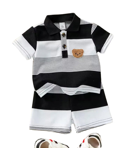 Children's black and white striped polo shirt with bear design and shorts on a textured surface.
