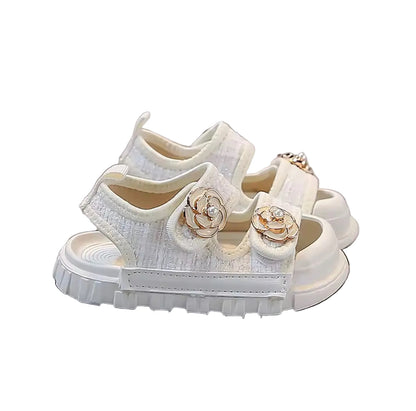 White sandal with floral embellishments on a gray background