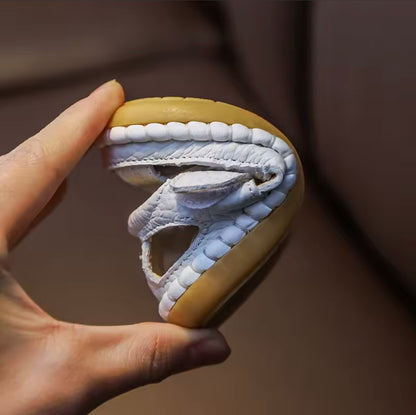 Hand holding a unique cookie with a design resembling a mouth and teeth on a brown background