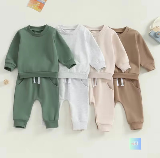 Four children's sweatshirt and pants sets in green, white, beige, and brown on a light background.