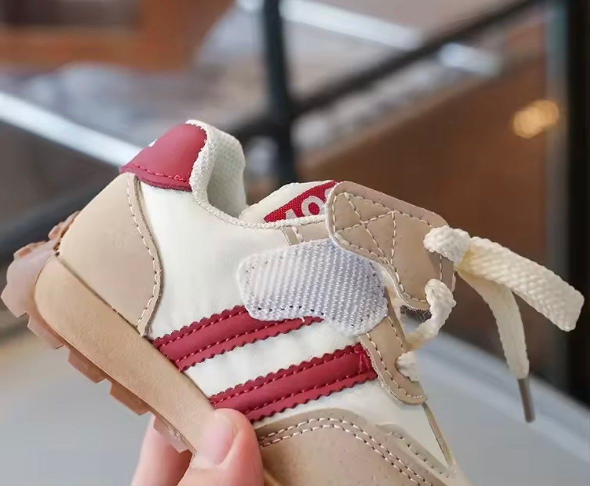 Beige and red sneaker held by a hand with a blurred background