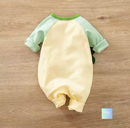 Baby romper with green sleeves on a wooden surface