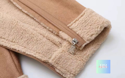 Close-up of a beige fleece jacket with a zipper and a decorative charm on a white background.