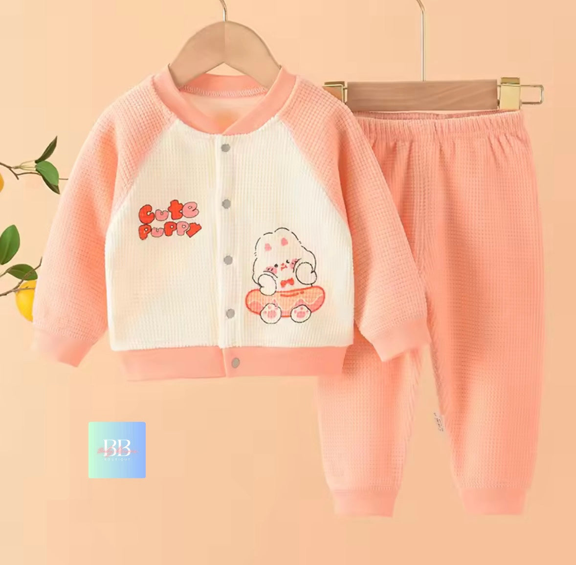 Children's pink outfit with cartoon design on a hanger against a beige background