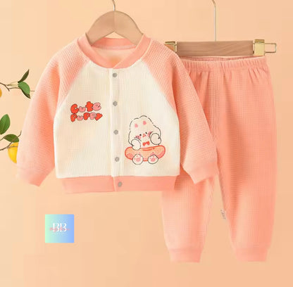 Children's pink outfit with cartoon design on a hanger against a beige background