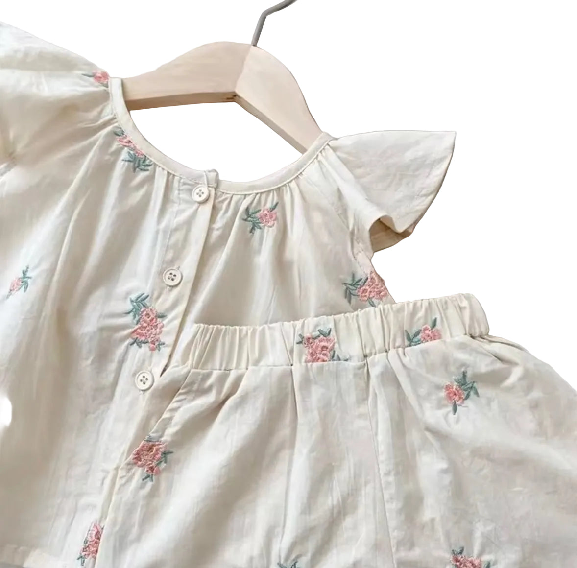 White children's outfit with floral embroidery on a light background