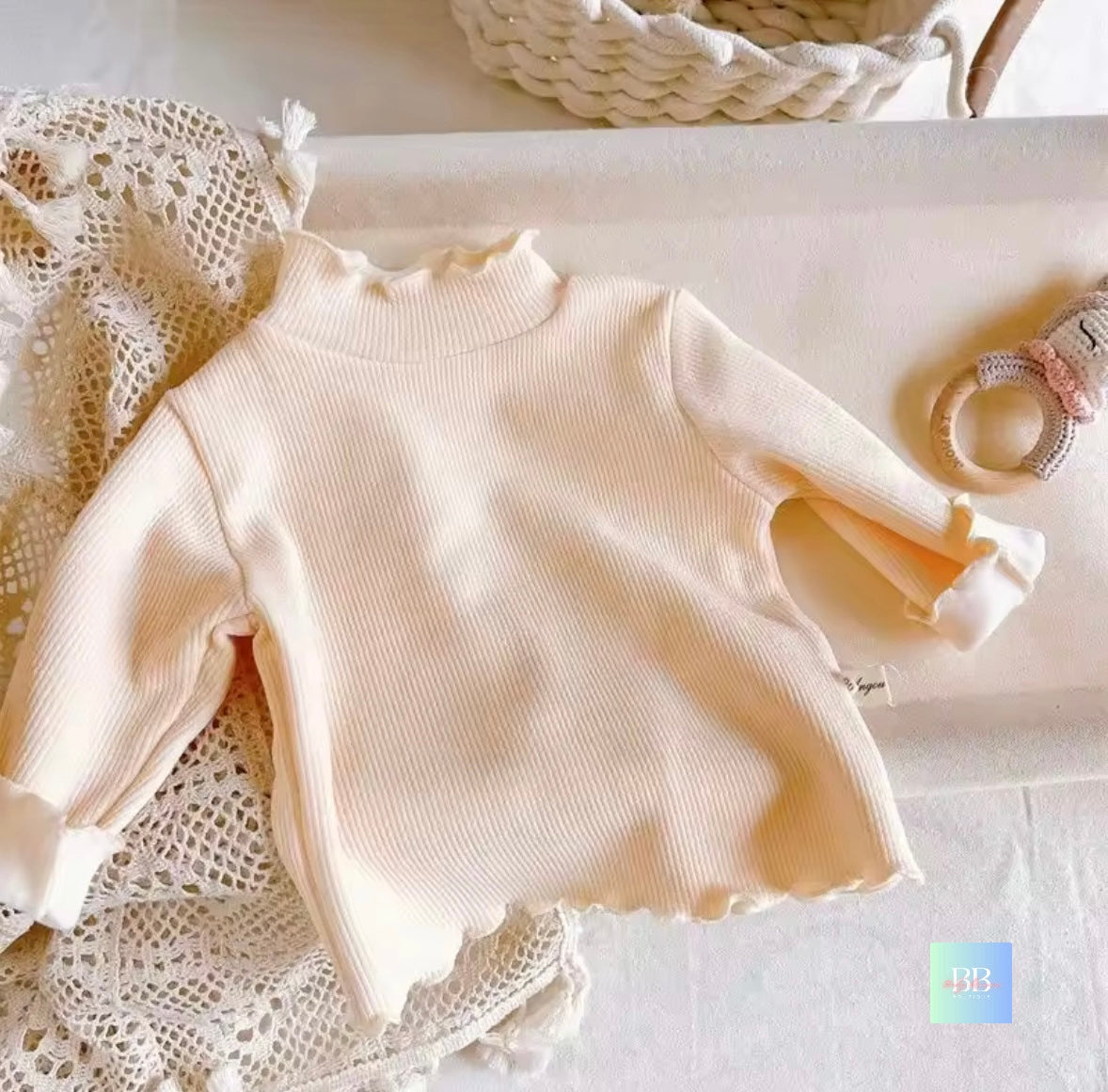 Beige long-sleeve top on a white surface with lace fabric