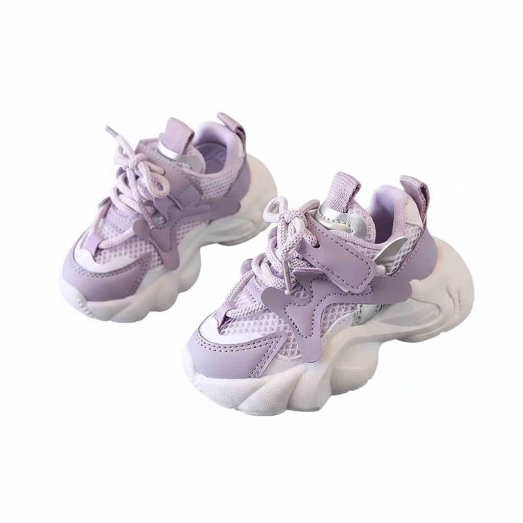 Purple children's sneakers on a gray surface with a hand holding one shoe.