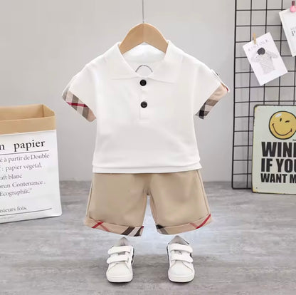 Children's outfit with white polo shirt and beige shorts on a hanger against a light gray background.