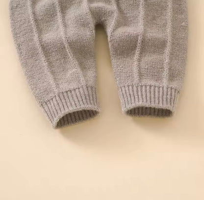 Gray knitted baby pants on a beige background