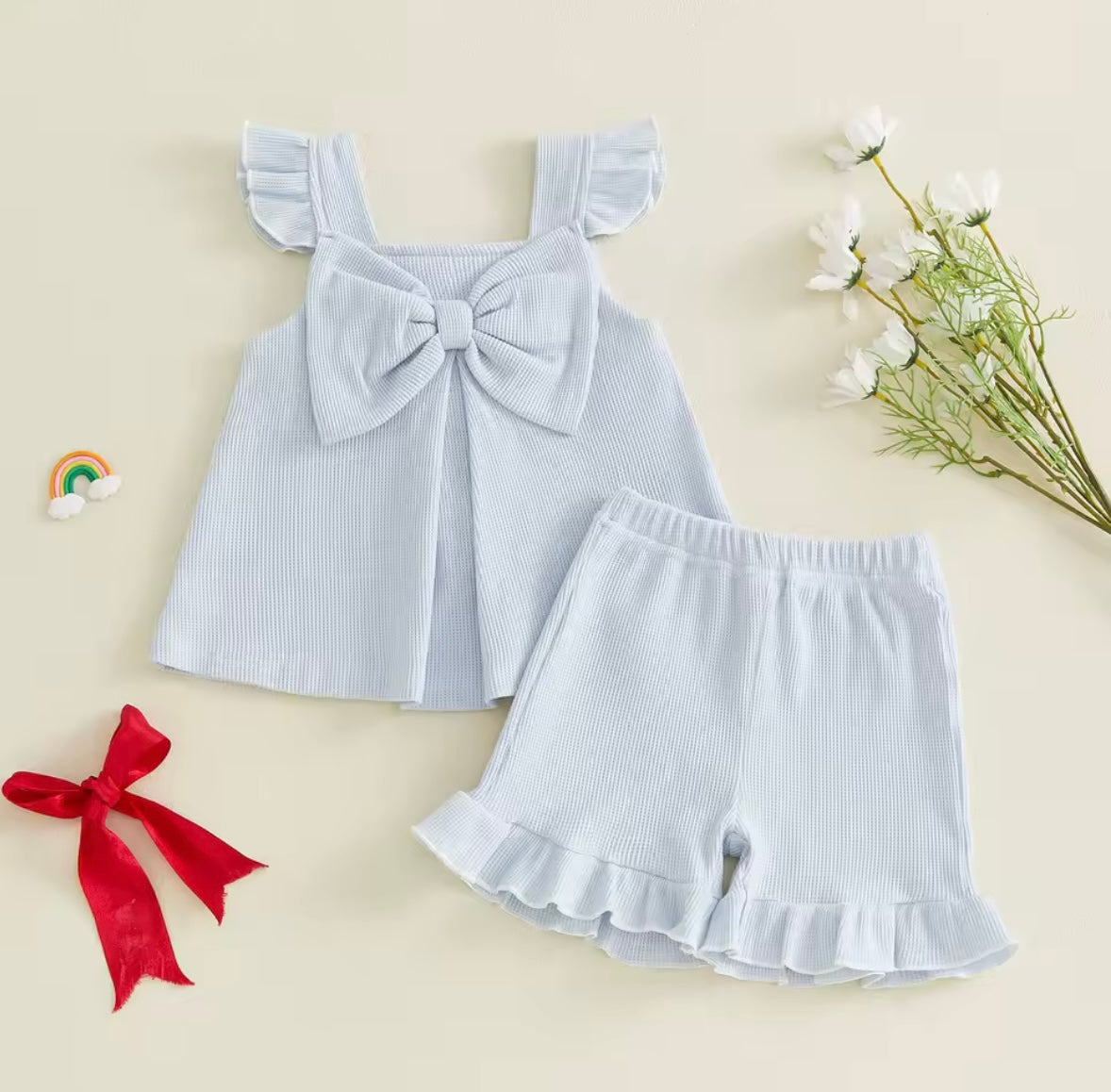 Light blue sleeveless top with bow and matching shorts on a beige background