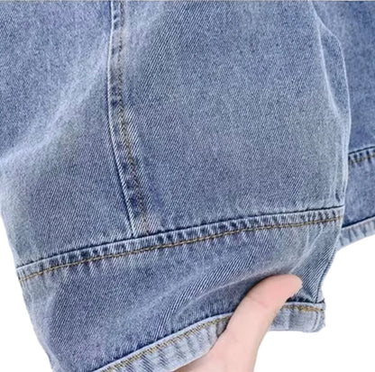 Close-up of a blue denim fabric with a hand pointing to the stitching detail.