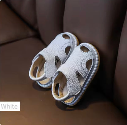 Pair of white children's sandals on a brown surface