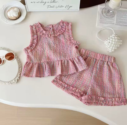 Pink children's outfit with ruffled details on a white surface.