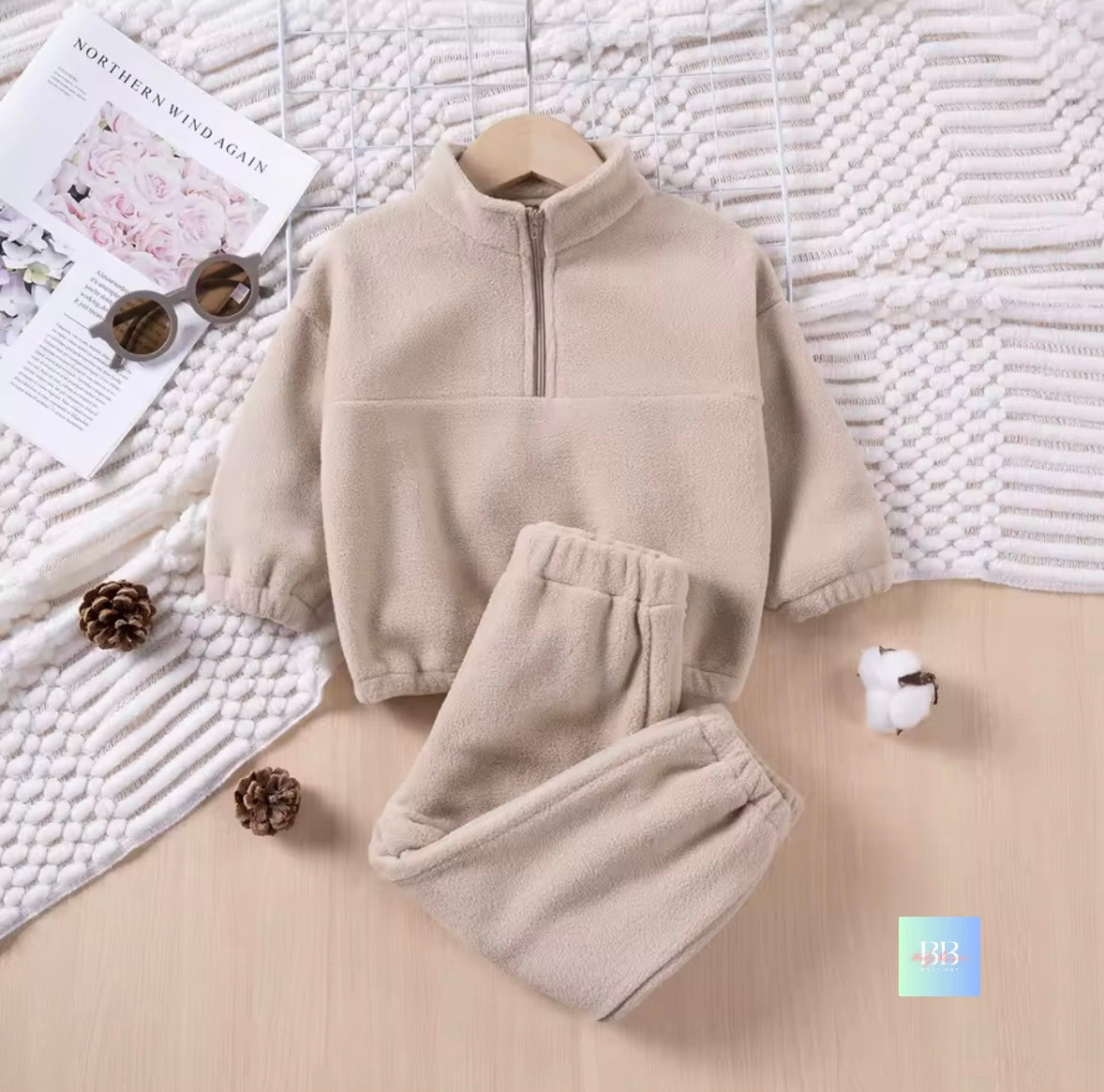 Beige fleece set on a textured surface with decorative items.