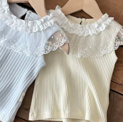 Two ribbed tank tops with lace trim on wooden hangers.