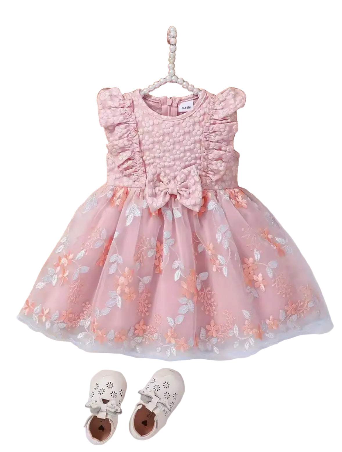Pink floral dress on a hanger with a hat, flowers, and shoes in the background