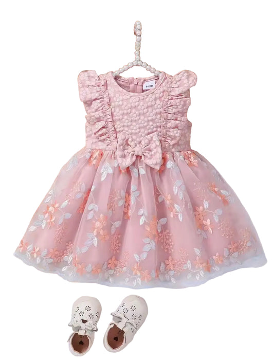 Pink floral dress on a hanger with a hat, flowers, and shoes in the background