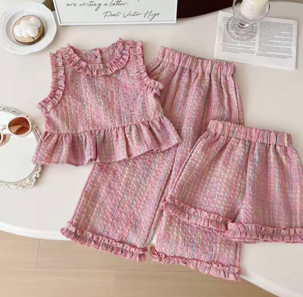 Pink ruffled children's outfit on a white surface with decorative items.