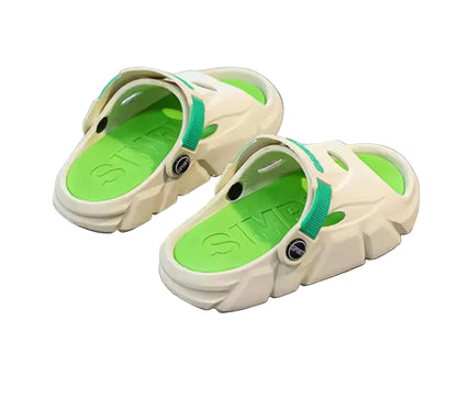 Pair of beige sandals with green soles on a gray surface