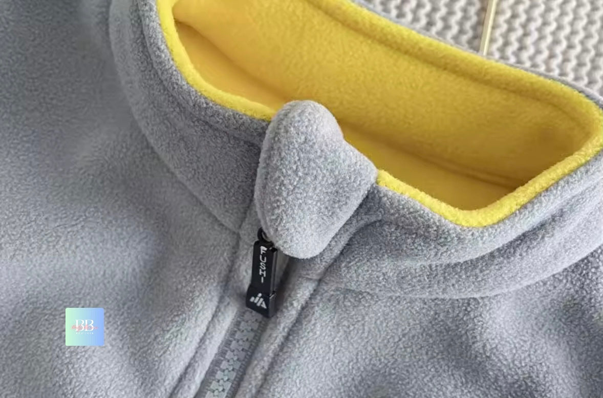 Gray fleece jacket with yellow lining and a brand tag on a textured background
