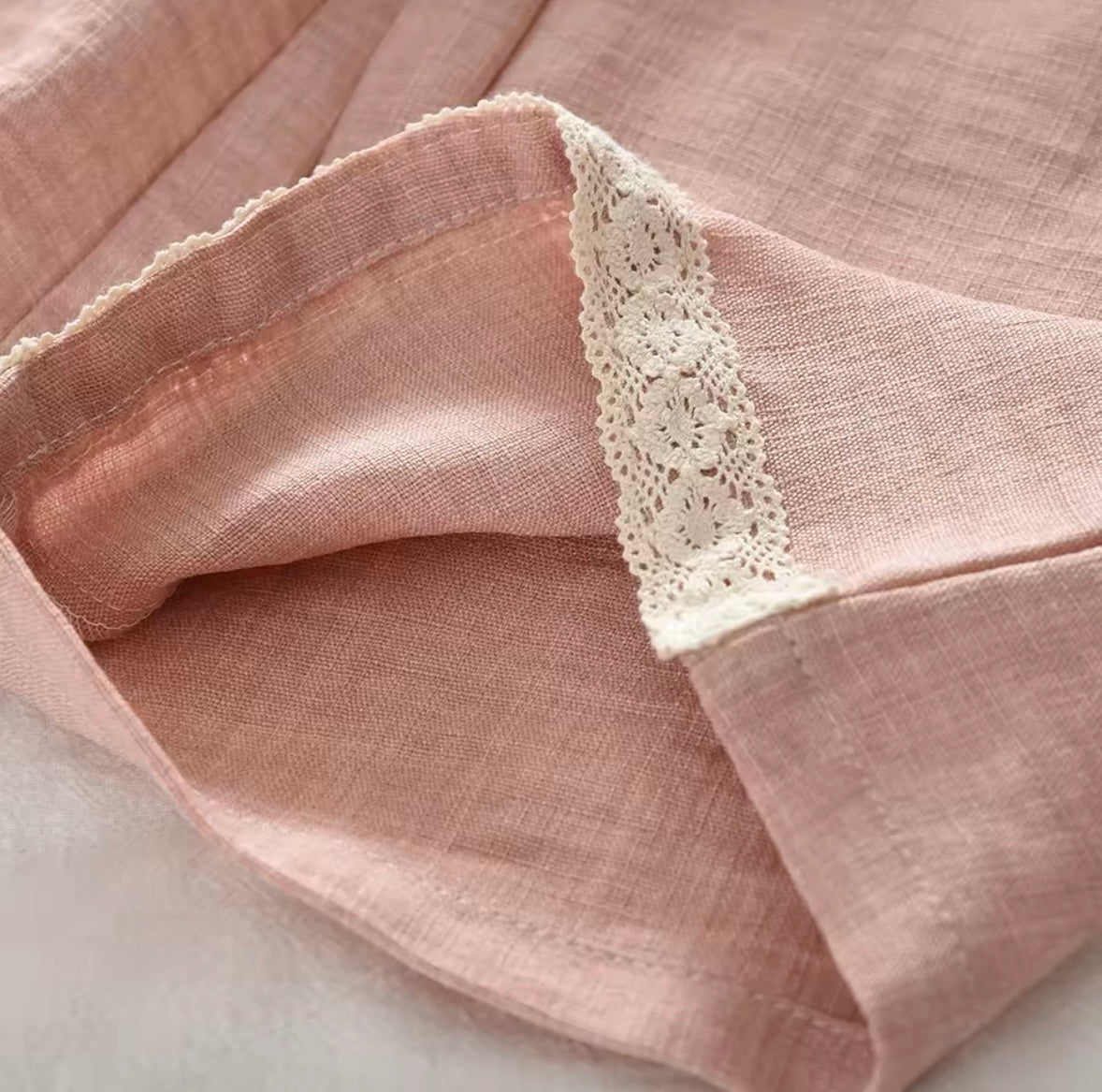 Close-up of pink fabric with lace trim on a light background