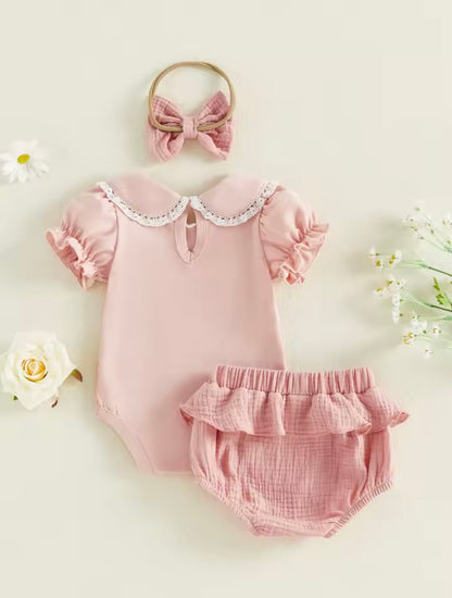 Pink baby romper with ruffles, matching bloomers, and a headband on a light background.