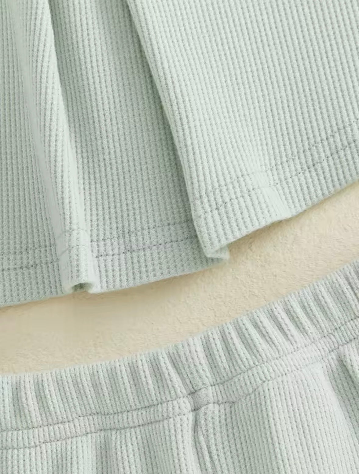 Close-up of light green textured fabric with a person's arm visible.