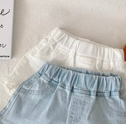 Light blue denim shorts and white top on a light gray surface with a blurred background.