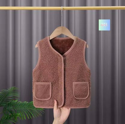 Brown fleece vest on a hanger against a gray curtain background