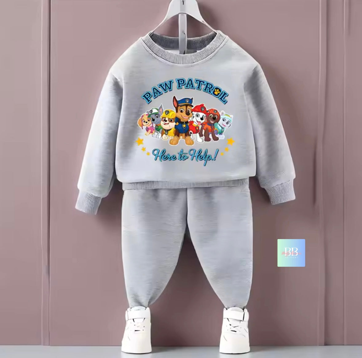 Gray 'Paw Patrol' children's outfit with cartoon characters on a hanger against a purple background.