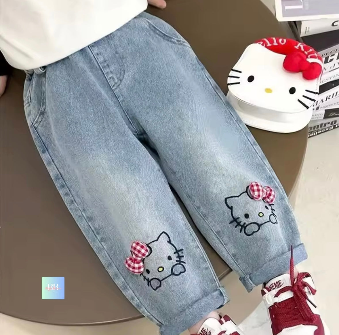 Light blue jeans with Hello Kitty patches on a brown surface.