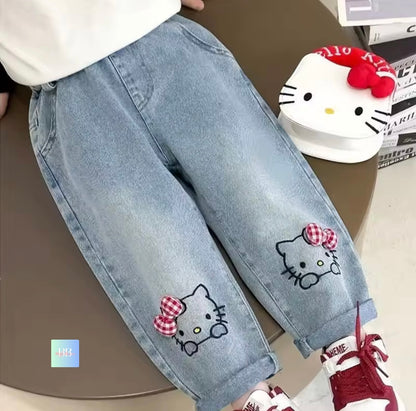 Light blue jeans with Hello Kitty patches on a brown surface.