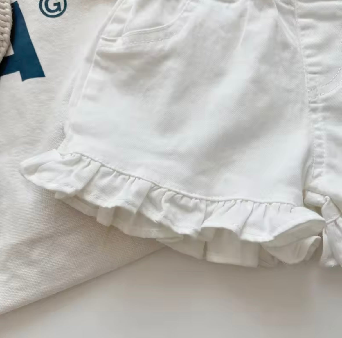 White shorts with ruffled hem on a light background