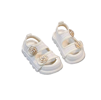 White children's sandals with floral decorations on a gray surface