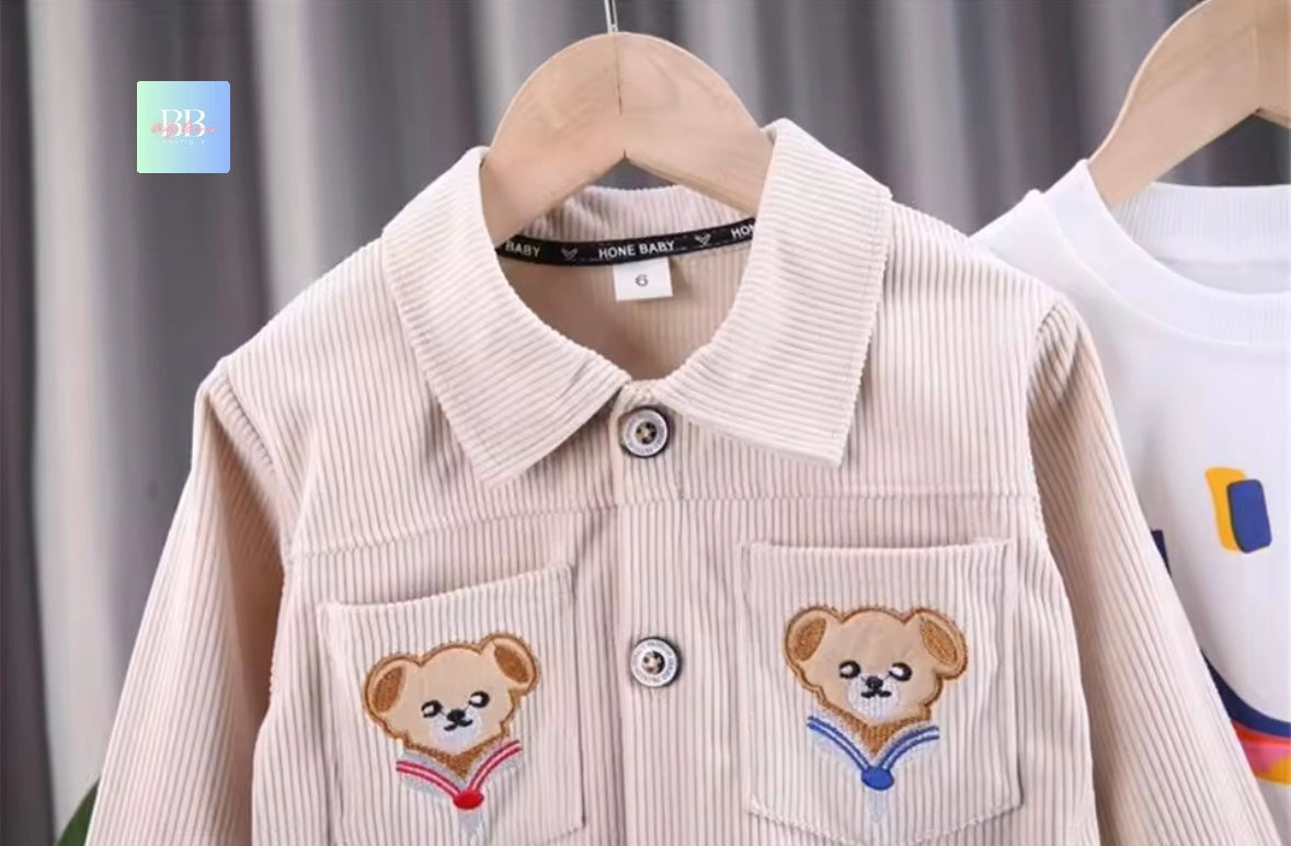 Children's shirt with teddy bear designs on a hanger against a neutral background