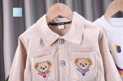 Children's shirt with teddy bear designs on a hanger against a neutral background