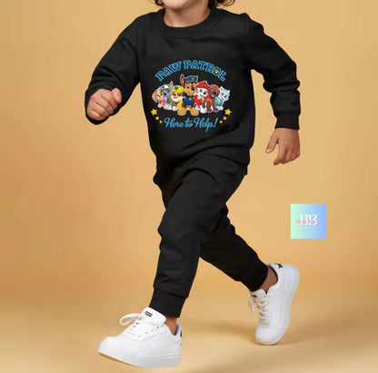 Child wearing a black 'Paw Patrol' sweatshirt and pants with white shoes on a beige background