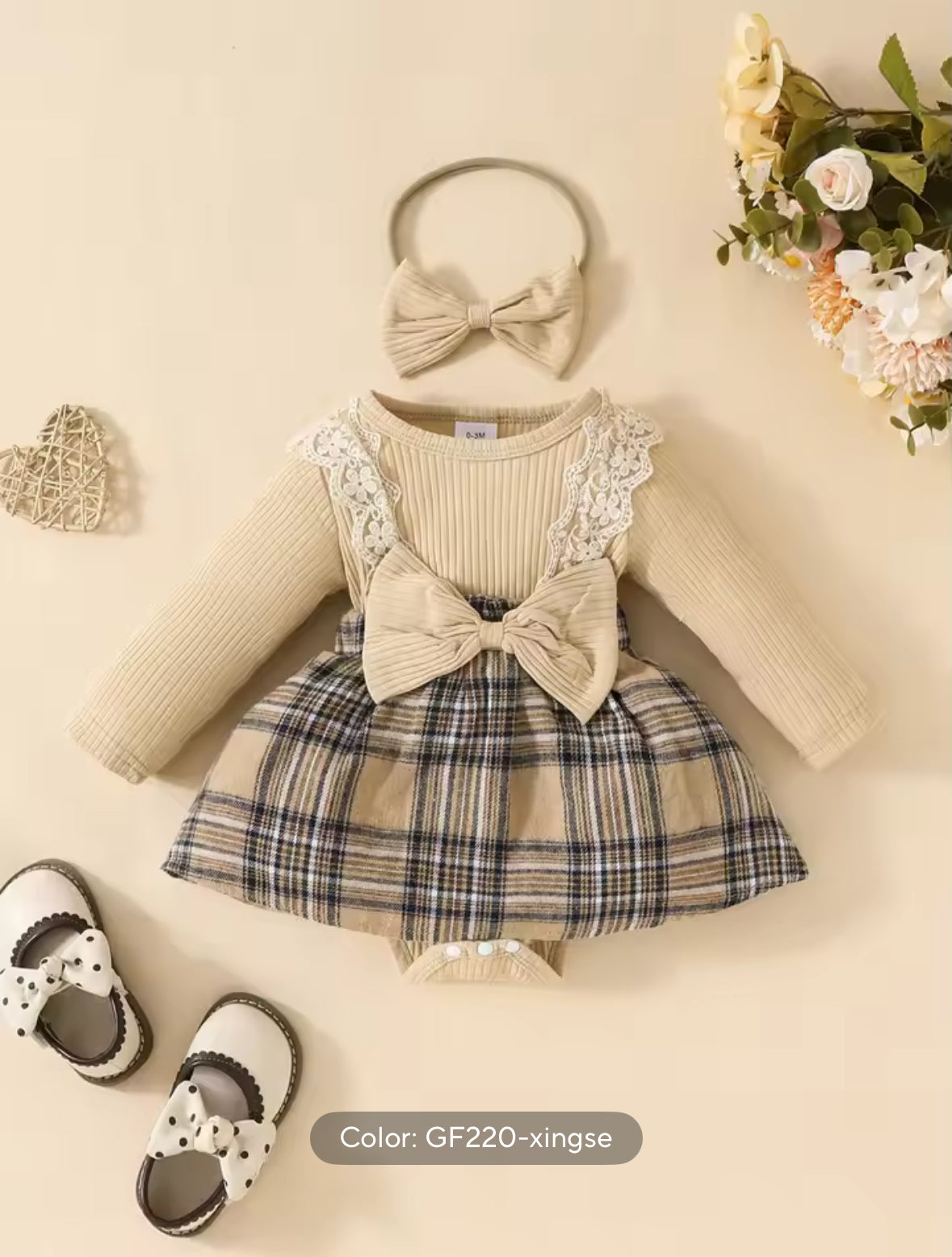 Baby outfit with dress, shoes, and headband on a beige background