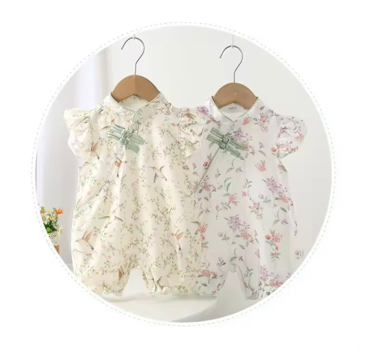 Two floral baby rompers hanging on wooden hangers against a white background